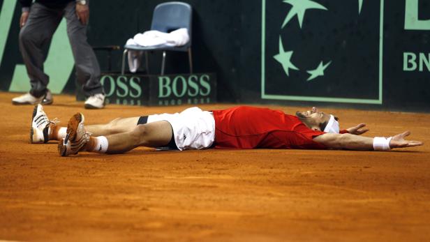 Ein Tennisspieler liegt erschöpft auf dem Sandplatz.