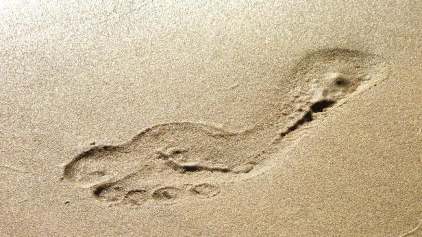 Ein einzelner Fußabdruck im goldenen Sand.