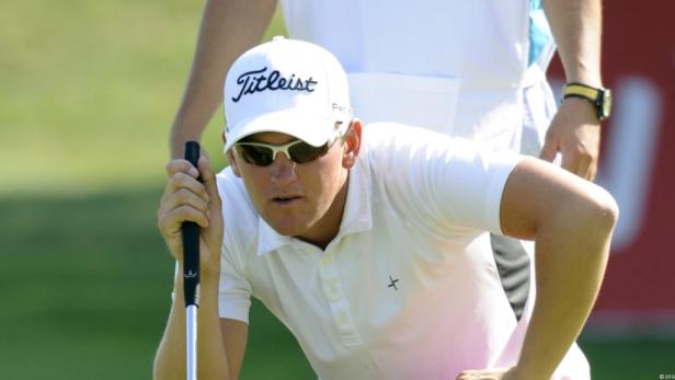 Ein Golfspieler mit Sonnenbrille und Kappe zielt mit seinem Putter.