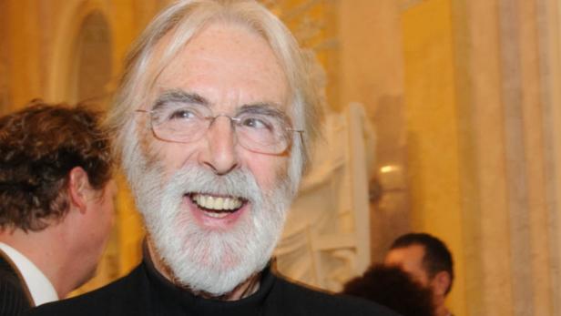 Ein lächelnder Mann mit Brille und Bart, möglicherweise bei einer Veranstaltung.