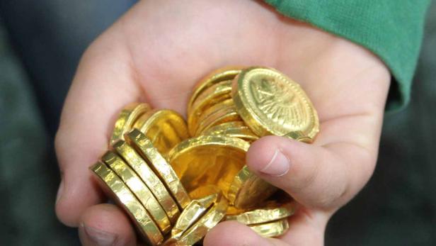Eine Hand hält eine Menge goldener Schokoladenmünzen.