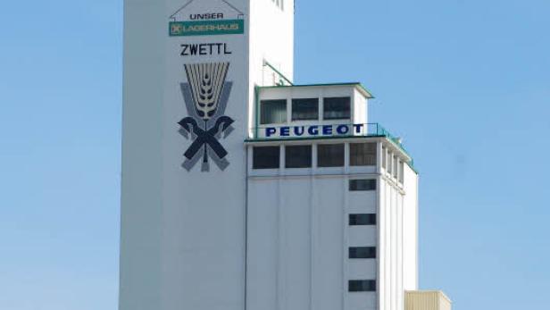 Ein hohes, weißes Lagerhaus mit dem Schriftzug „Unser Lagerhaus Zwettl“ und dem Peugeot-Logo.