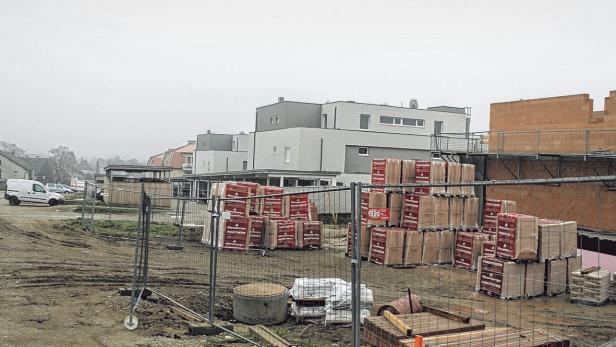 Auf einer Baustelle lagern Ziegelsteine vor neuen Wohnhäusern.