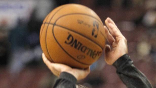Ein Basketballspieler hält einen Spalding-Basketball in der Hand.