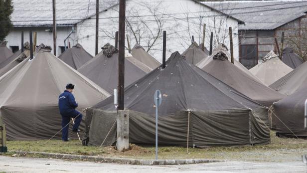 Ein Mann in Uniform steht vor einer Gruppe von Zelten.