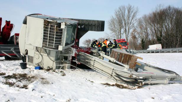 Ein umgestürzter Kran liegt im Schnee, während Rettungskräfte vor Ort sind.