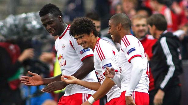 Drei Fußballspieler von RB Leipzig feiern gemeinsam auf dem Spielfeld.