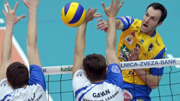 Ein Volleyballspieler blockt den Ball am Netz.