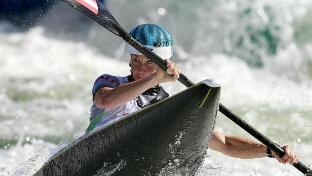 Eine Frau paddelt in einem Kajak durch das Wildwasser.