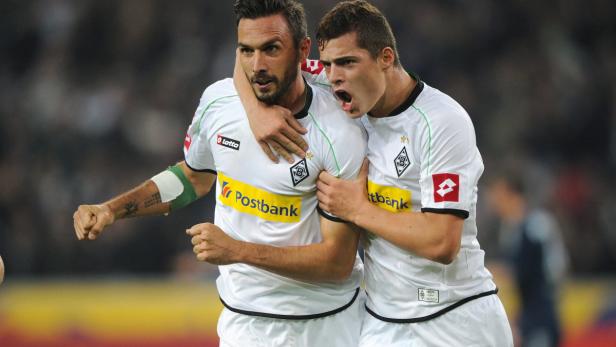 Zwei Fußballspieler von Borussia Mönchengladbach umarmen sich jubelnd.