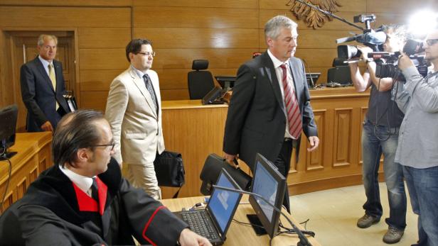 Mehrere Personen in einem Gerichtssaal, darunter ein Richter und Kameraleute.