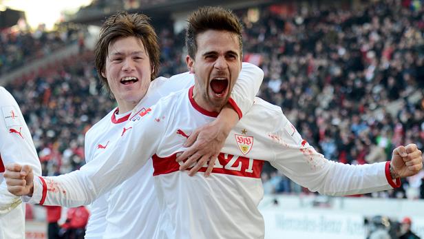 Zwei jubelnde Fußballspieler des VfB Stuttgart umarmen sich vor einer Zuschauermenge.