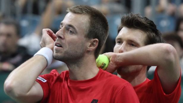 Zwei Tennisspieler in roten Trikots während eines Spiels.