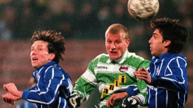 Drei Fußballspieler kämpfen um einen Ball in der Luft.