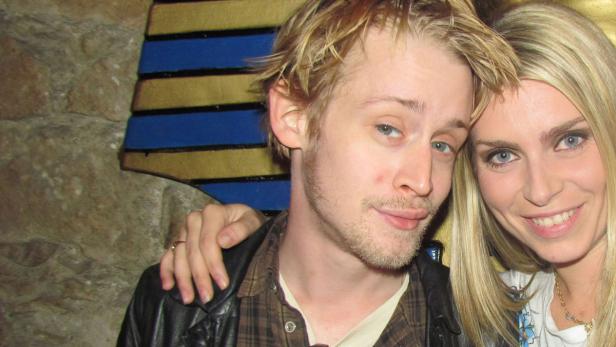 Macaulay Culkin posiert mit einer blonden Frau für ein Foto.