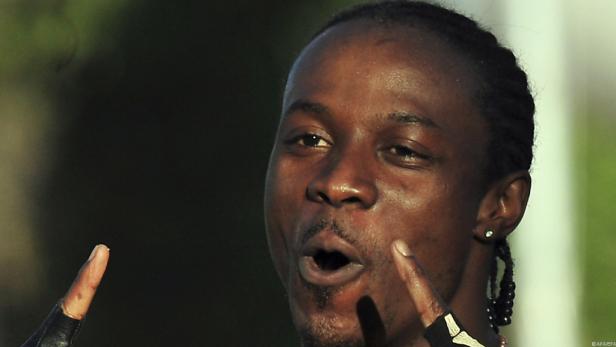 Ein Mann mit Zöpfen gestikuliert mit erhobenem Zeigefinger.