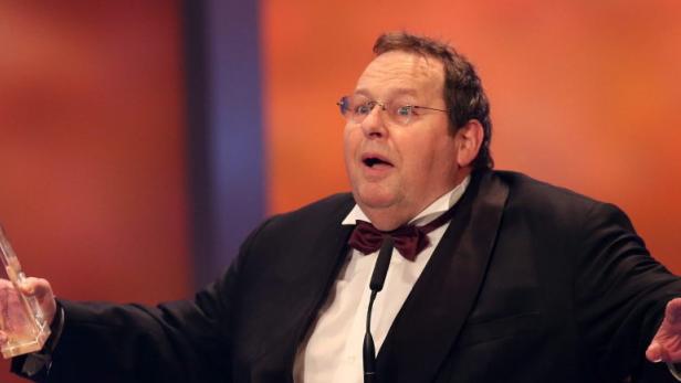Kopie von GERMANY TELEVISION AWARDS Ein Mann im Smoking hält einen Preis in der Hand und wirkt überrascht.