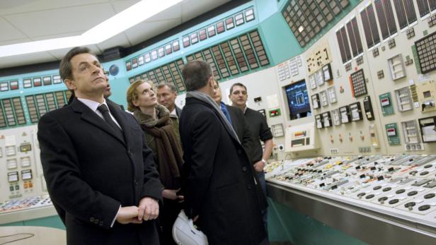 Nicolas Sarkozy und eine Gruppe von Personen in einem Kontrollraum eines Kernkraftwerks.