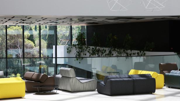 Ein heller, moderner Wartebereich mit farbenfrohen Sofas und Blick auf üppiges Grün.
