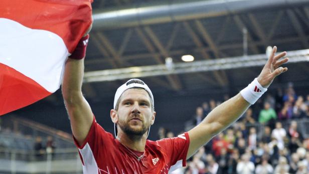 Ein Tennisspieler feiert mit der österreichischen Flagge im Publikum.