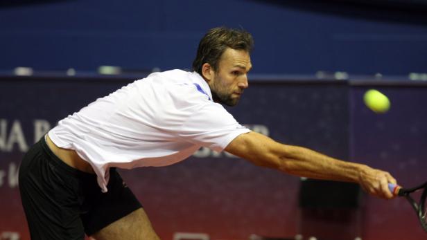 Ein Tennisspieler schlägt einen Ball mit seinem Schläger.