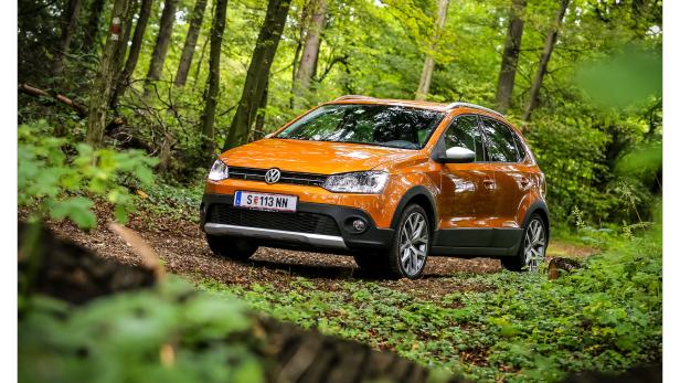 Ein orangefarbener VW Cross Polo fährt auf einem Waldweg.