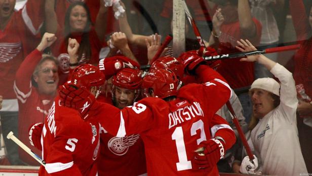 Eishockeyspieler der Detroit Red Wings feiern ein Tor vor jubelnden Fans.