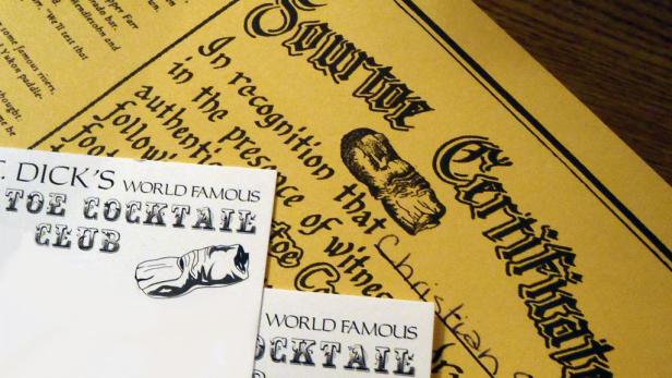 Ein Zertifikat des „Sourtoe Cocktail Club“ und eine Visitenkarte von „S. Dick's World Famous Toe Cocktail Club“.