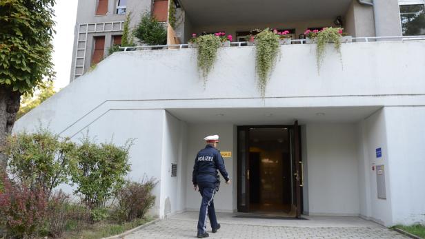 Ein Polizist betritt ein Gebäude mit Blumenkästen auf dem Balkon.