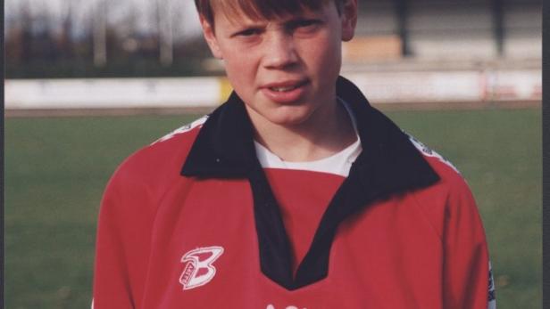 Ein junger Mann im roten Trikot des ASV Vösendorf steht auf einem Sportplatz.