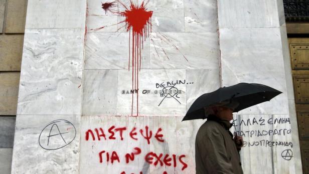 REUTERSA man passes the defaced facade of the Bankof Greece after a night of violence which followed the Greek parliament approval of a deeply unpopular austerity bill in Athens, February 13, 2012. Police said 150 shops were looted in the capital and 48 b