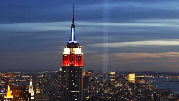 Das Empire State Building leuchtet rot, weiß und blau über der Skyline von New York City.