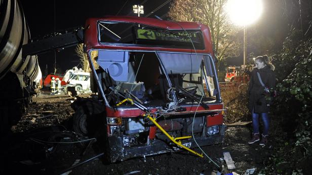 Ein zerstörter roter Bus nach einem Unfall bei Nacht.