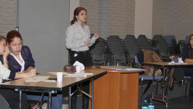 Eine Frau hält einen Vortrag vor einem Publikum in einem Konferenzraum.