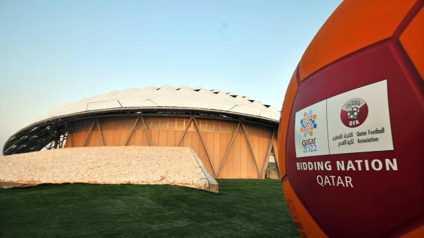 Ein Fußball mit dem Logo der Bewerbung Katars für die FIFA Fussball-Weltmeisterschaft 2022 vor einem Stadion.