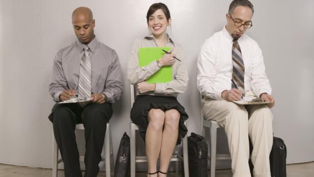 Smiling woman seated between men filling out applications