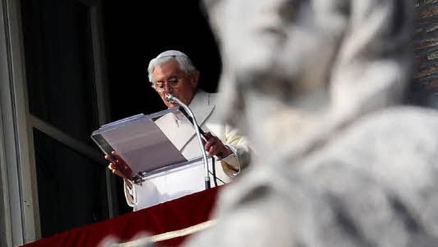 Papst Benedikt XVI. spricht von einem Balkon aus vor einer Statue.