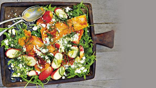 Ein Salat mit Kürbis, Radieschen, Feta und Dill auf einem Holzbrett.