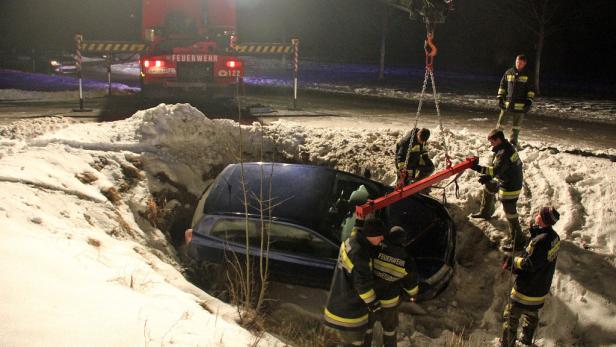 Ein Auto ist in einen Graben voller Schnee gerutscht und wird von der Feuerwehr geborgen.