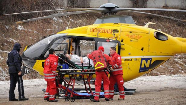 Rettungskräfte verladen einen Patienten in einen gelben Rettungshubschrauber.