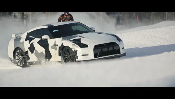 Ein weißer Nissan GT-R mit Tarnmuster fährt auf einer schneebedeckten Straße.
