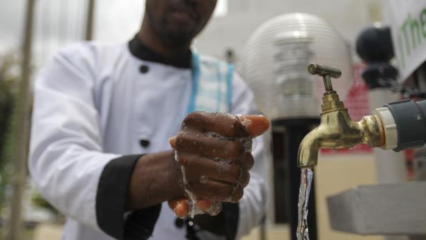 Ein Koch wäscht sich die Hände mit Seife unter einem Wasserhahn.