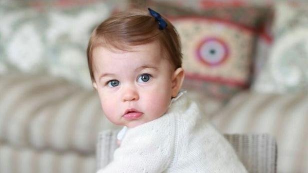 Ein Baby mit blauen Augen und einer blauen Schleife im Haar blickt in die Kamera.