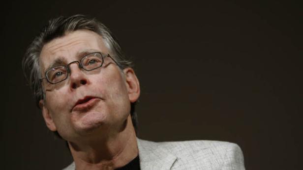 Porträt von Stephen King mit Brille vor dunklem Hintergrund.