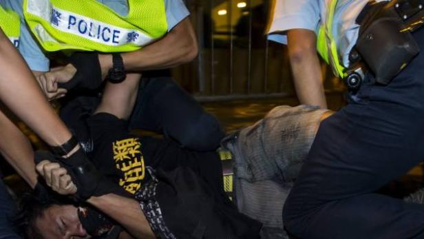 Mehrere Polizisten nehmen eine Person fest.