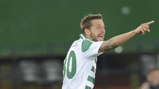 Ein Fußballspieler in einem weißen Trikot mit der Nummer 30 gestikuliert und scheint Anweisungen zu geben.