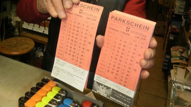 Eine Person hält zwei rosa Parkscheine in der Hand.