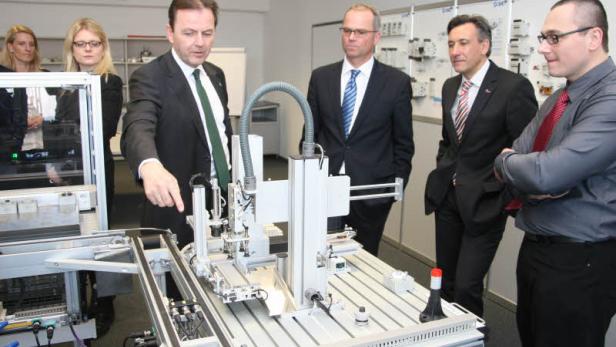 Eine Gruppe von Männern betrachtet eine industrielle Fertigungsanlage.