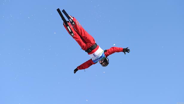 Eine Skifahrerin macht einen Sprung vor blauem Himmel.