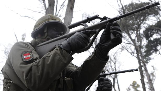 Ein Soldat mit Gesichtsbemalung zielt mit einem Steyr AUG-Gewehr.